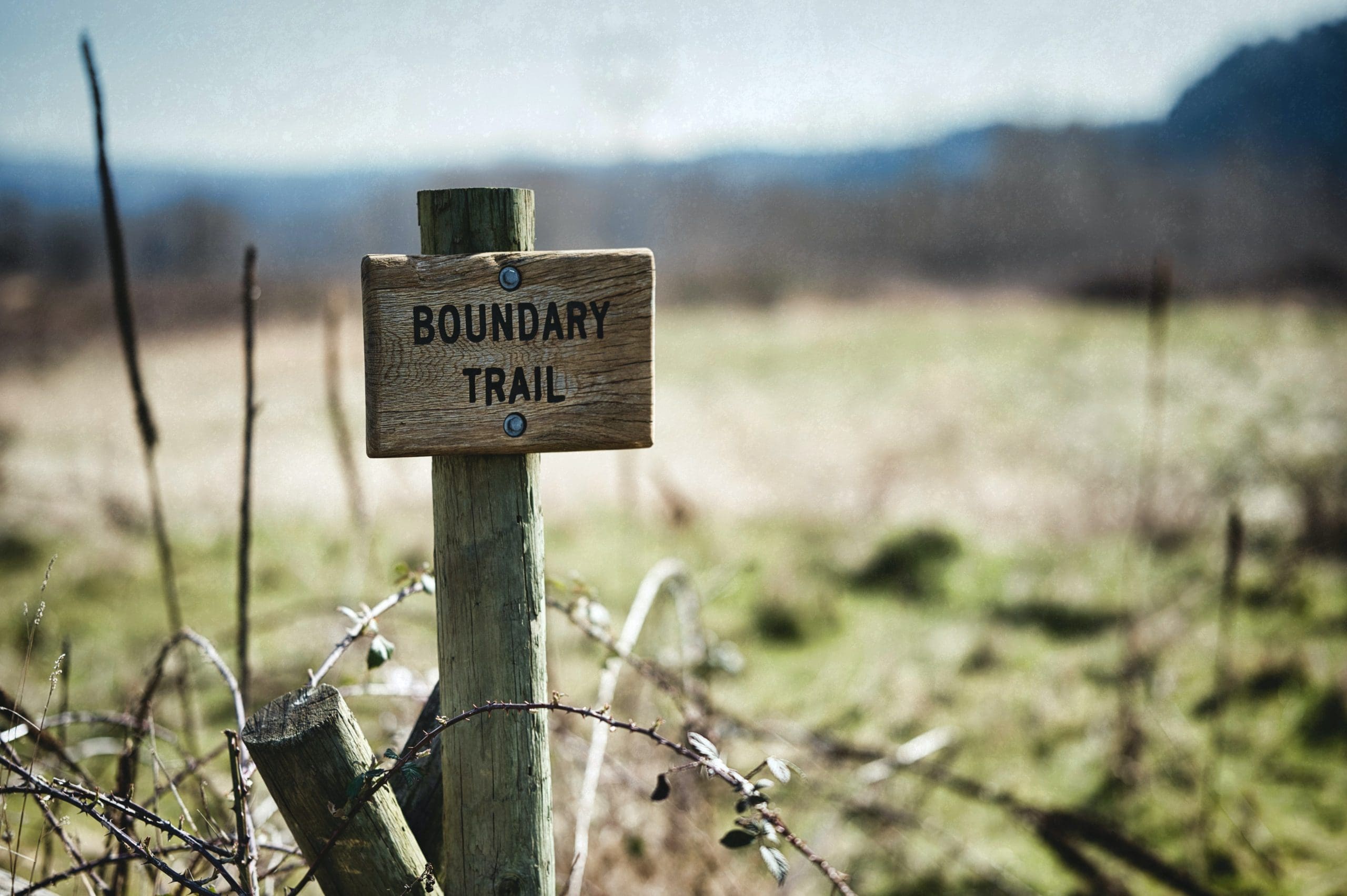 a brown sign showing a boundary line, Boundaries. Boundary.